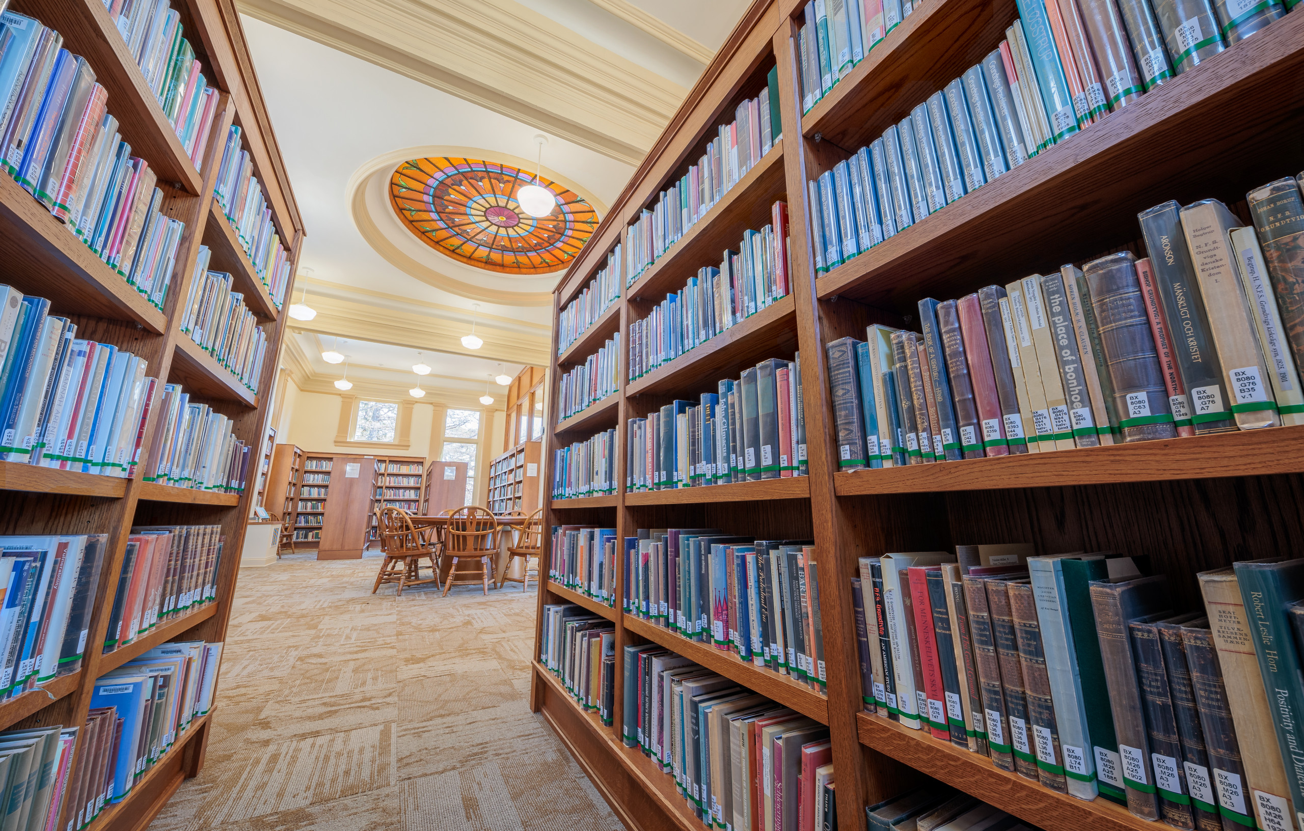 Interior of Steensland Hall, featuring a bookshelf on both sides, a centered circular table, and the skylight on the ceiling.